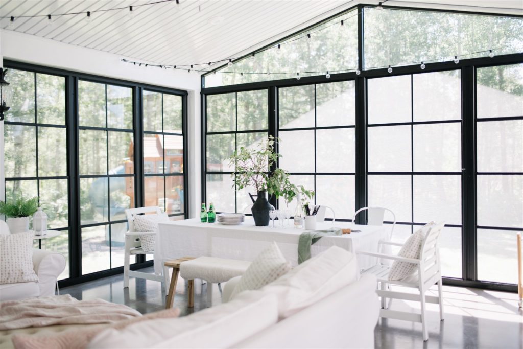 a large sunroom with floor to ceiling black windows and a vaulted ceiling