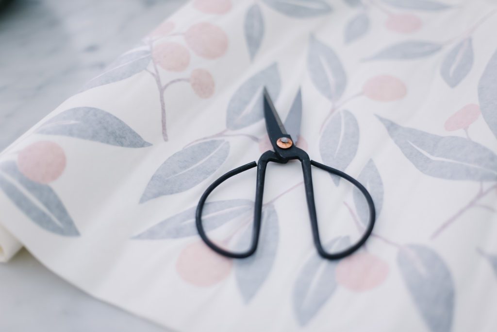 A pair of black scissors on top of wallpaper