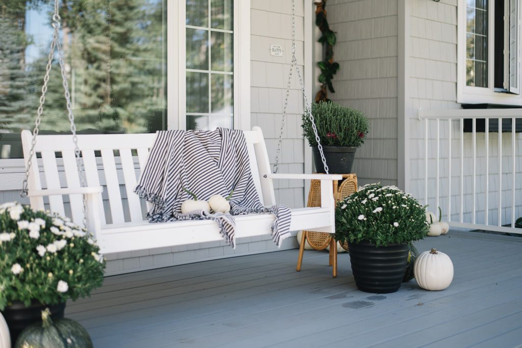 front porch swing with fall mums and white pumpkins