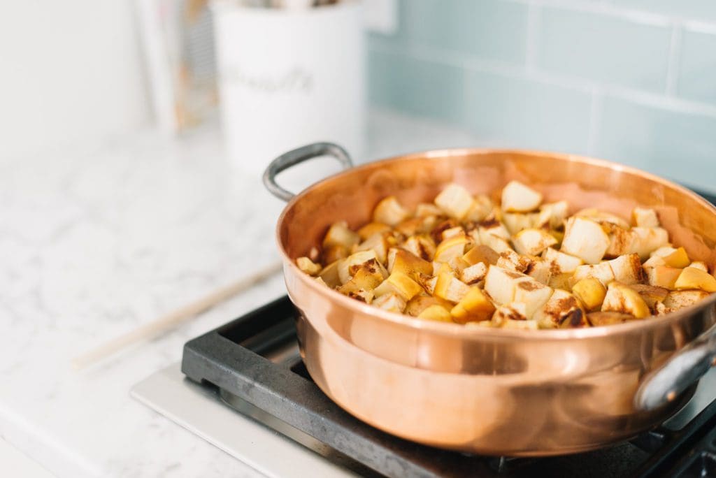 applesauce cooking on the stove in a copper pot