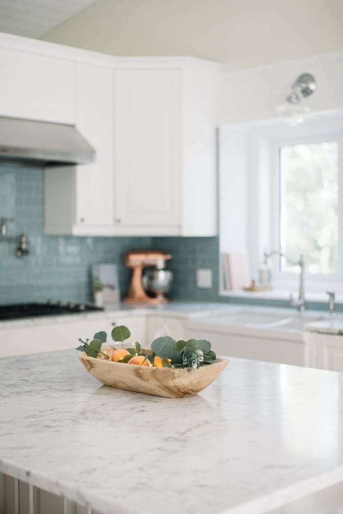 vintage bread bowl filled with peaches and greens on kitchen island