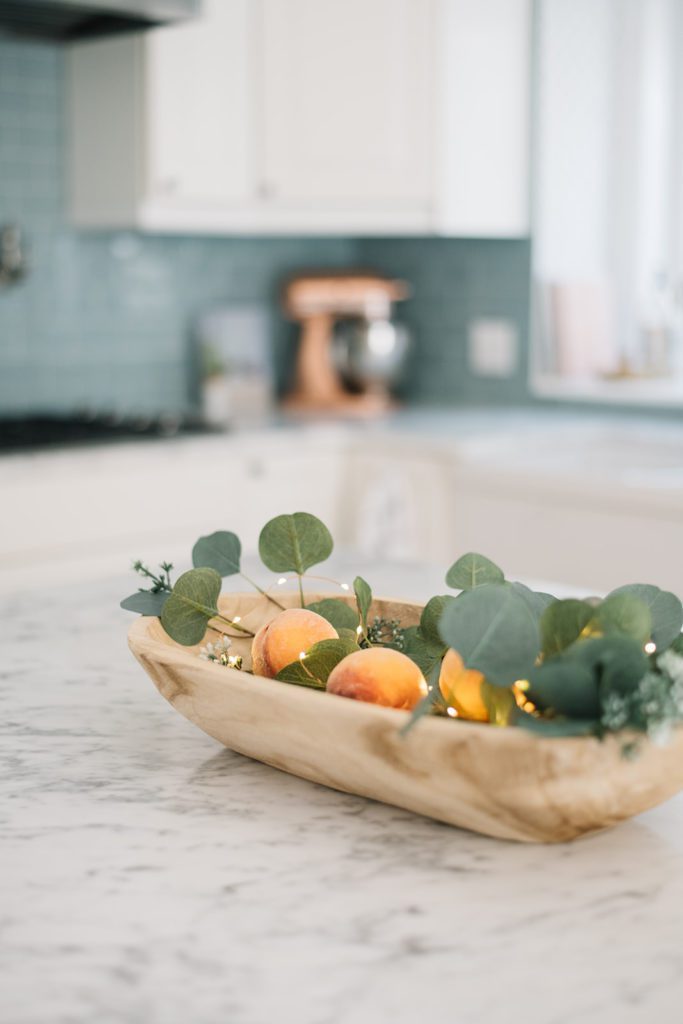 bowl of peaches and eucalyptus on kitchen counter