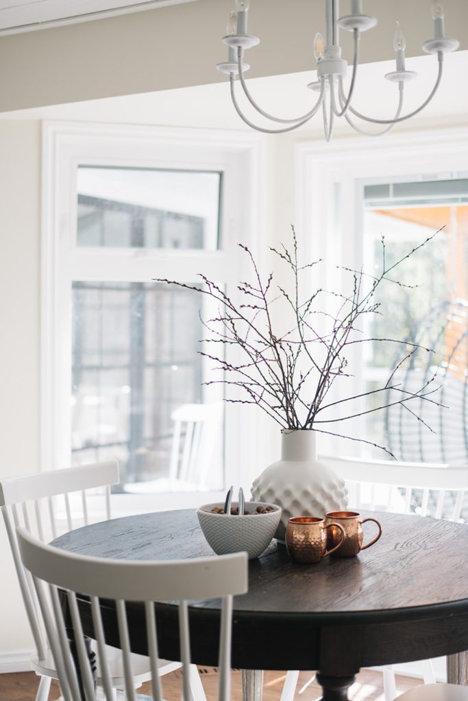 dining room table with copper mugs and vase of branches