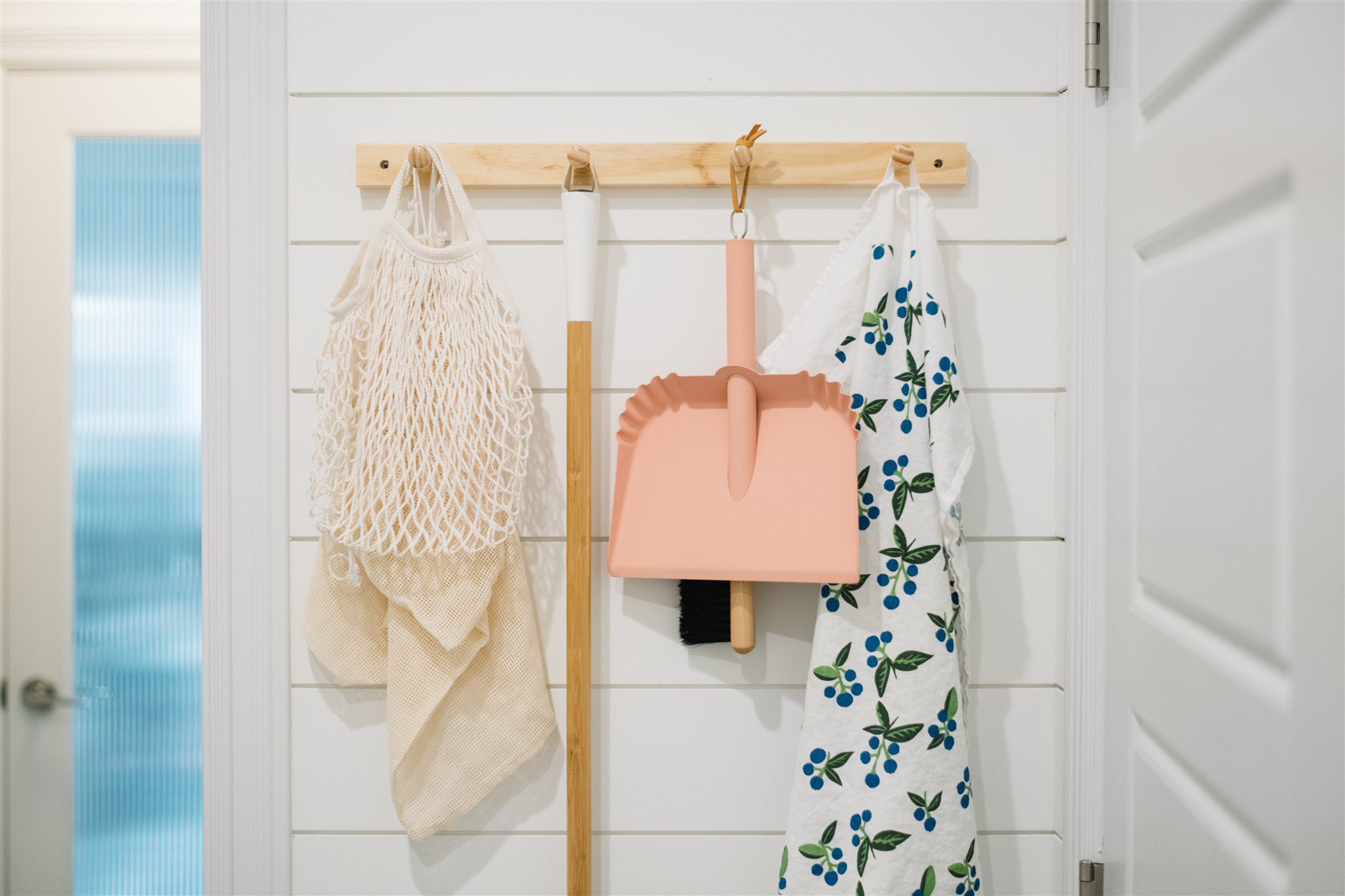 peg rail with dustpan, tea towel and market bags hung on it
