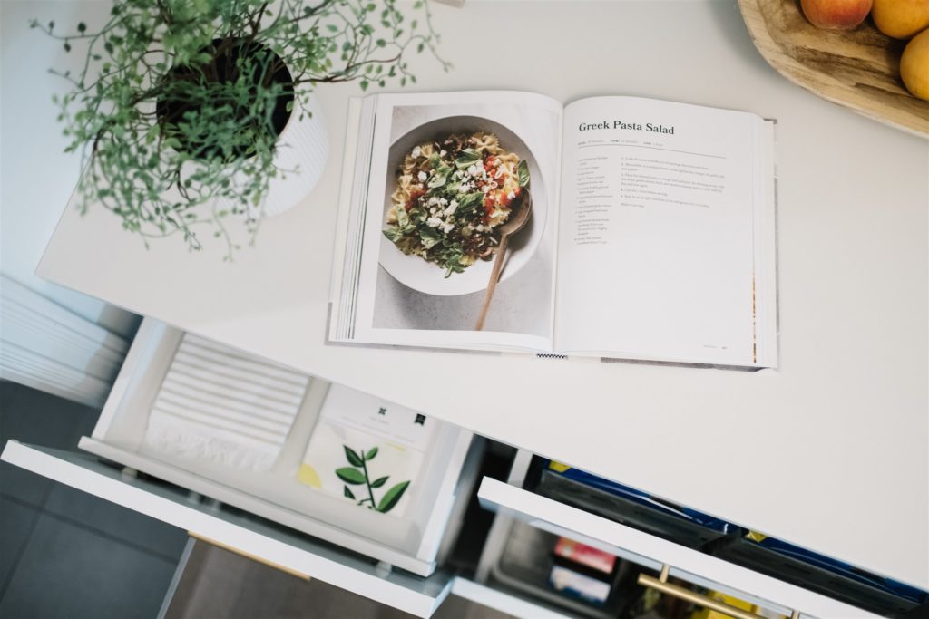 A cookbook sits open on a kitchen counter