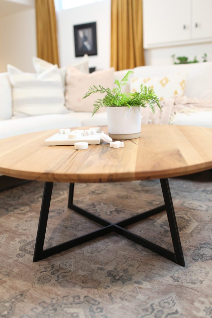 wooden coffee table with a fern on top and black metal legs