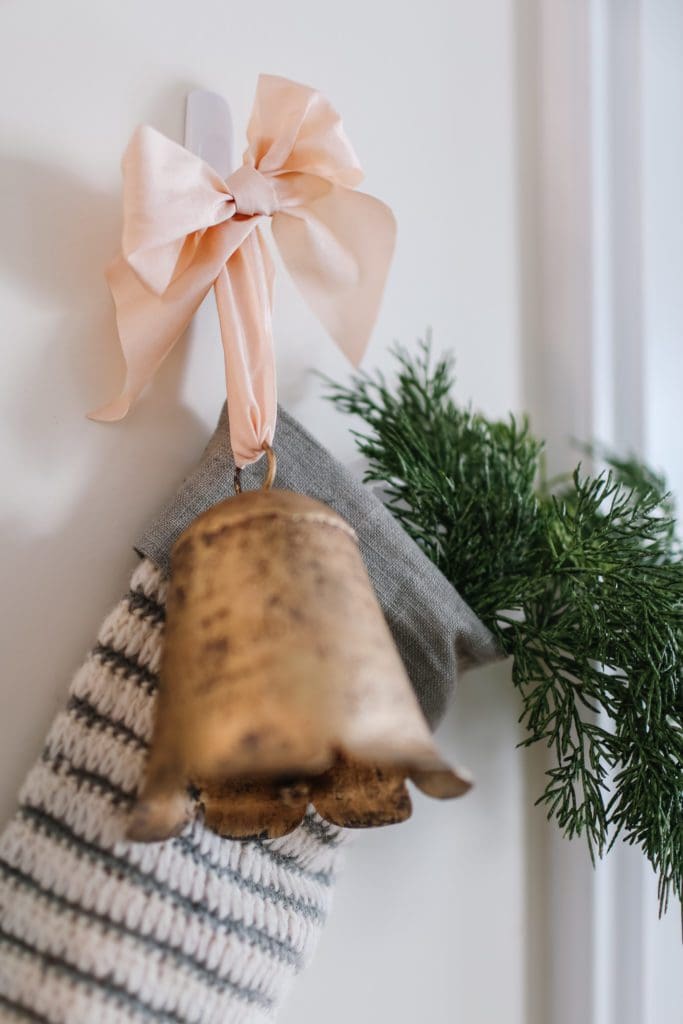 A close up of a brass bell and pink ribbon