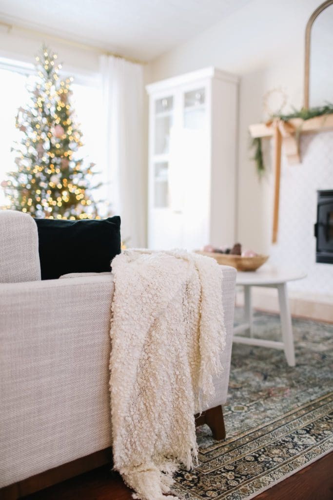 A white throw blanket on the side of a couch