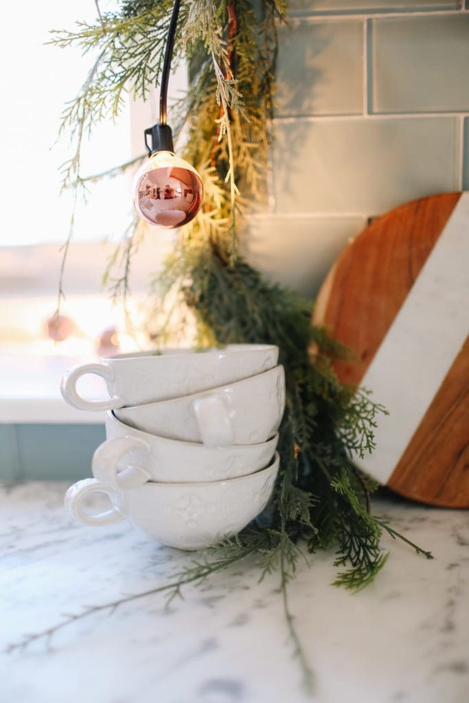 A stack of coffee mugs and a copper light string