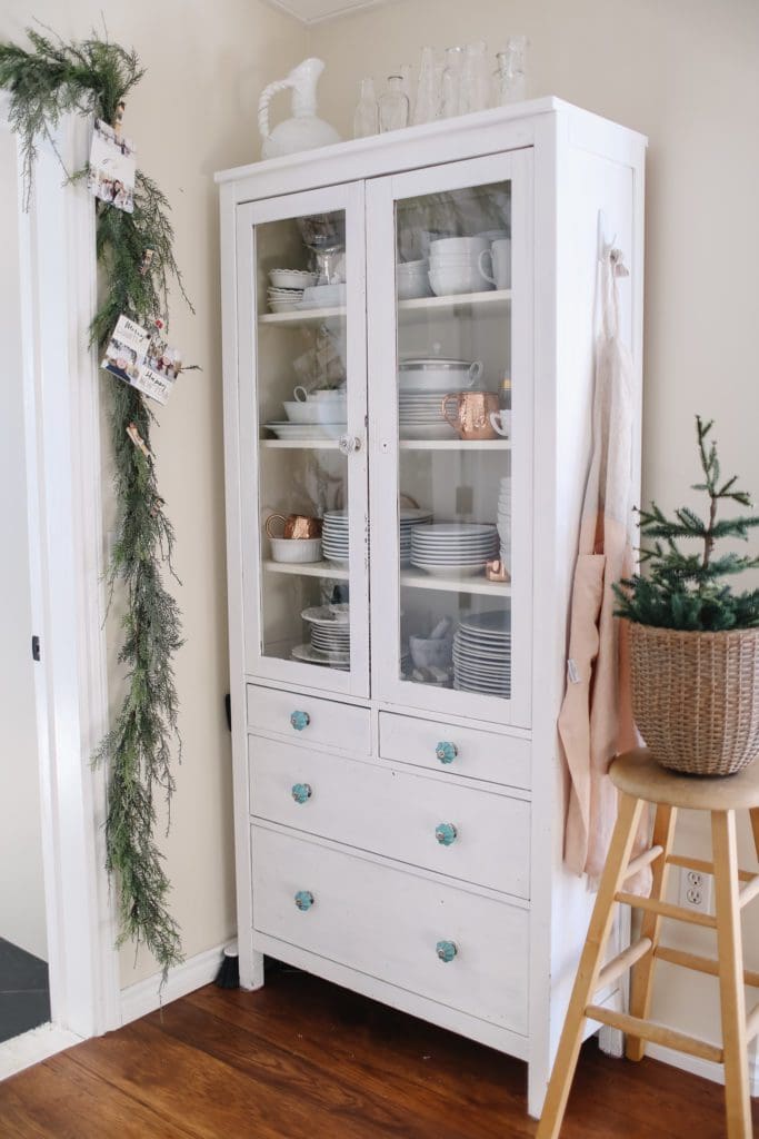 Hutch full of white dishes with Christmas garland 