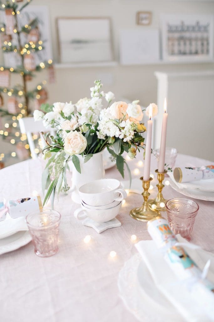 A vase of flowers on a table with a pink tablecloth and accessories