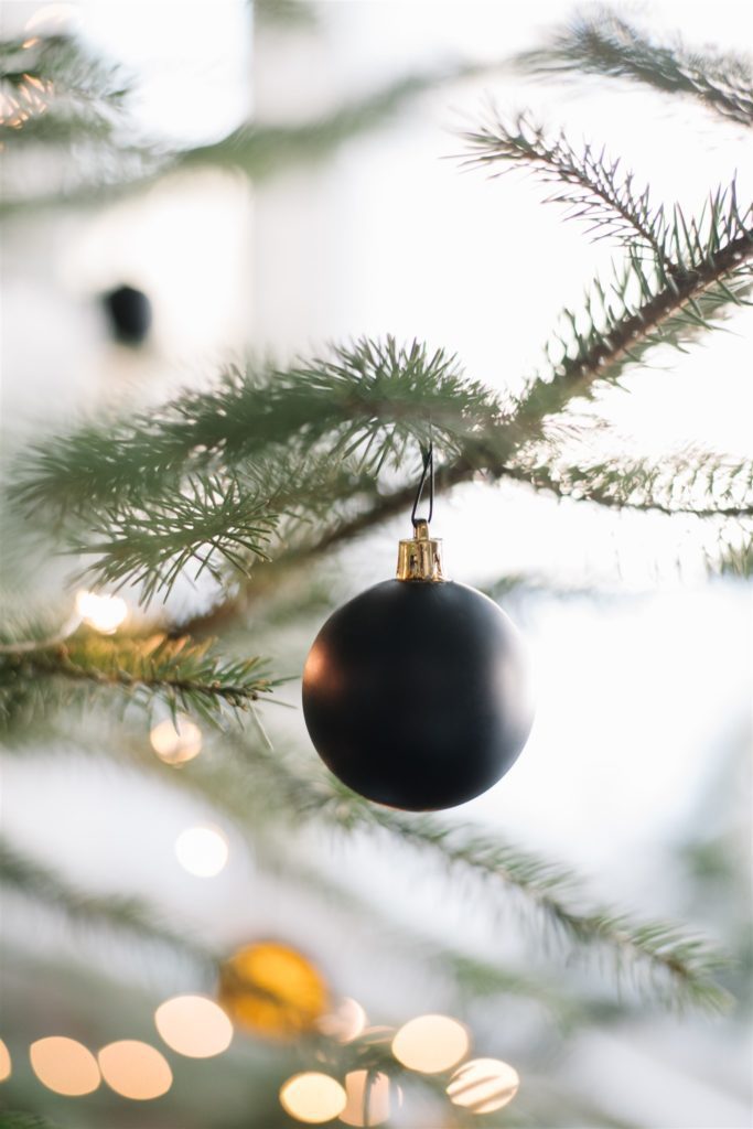 A close up of a black round ball Christms tree ornament