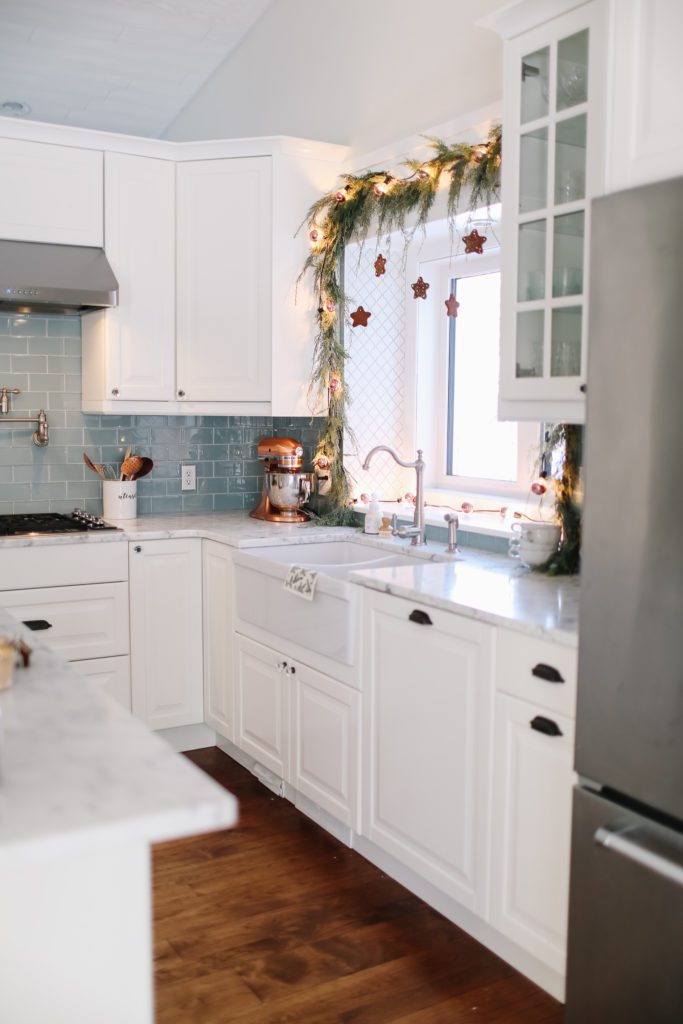 white kitchen with copper lights, and garland over the window