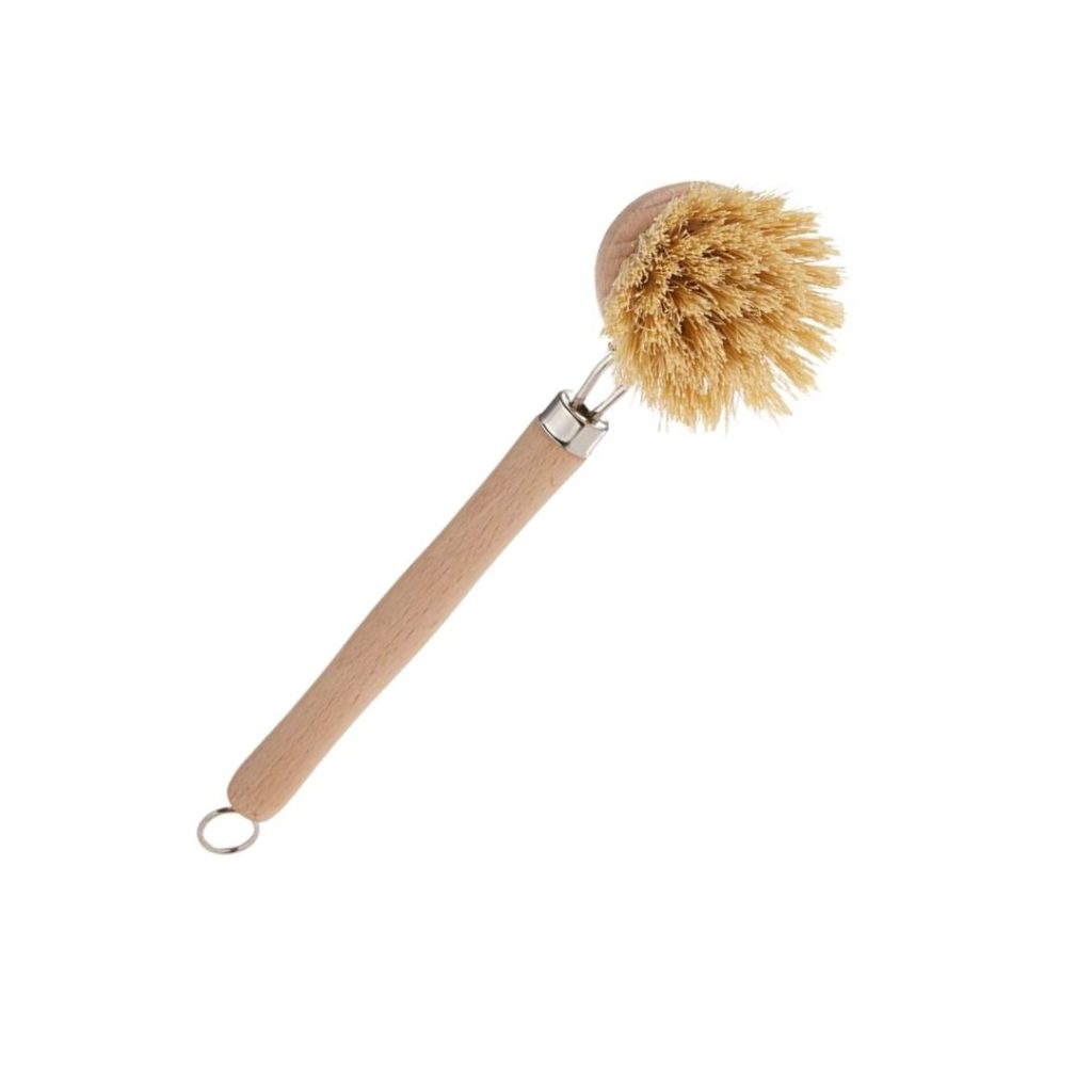 A close up of a kitchen scrub brush with a long wooden handle and natural bristles