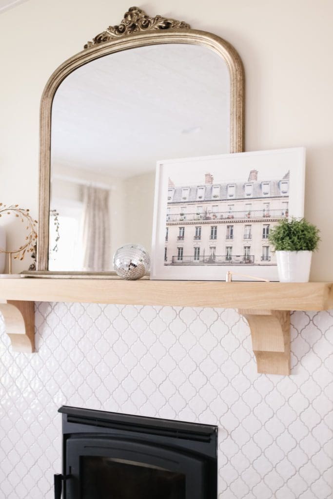 A fire place mantle with a mirror, art, plant and disco ball