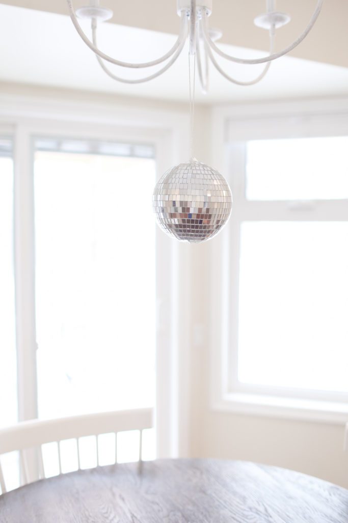 A disco ball hangs in front of large windows