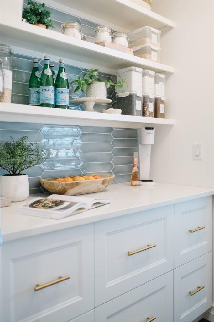 A pantry with open shelves and blue backsplash tile