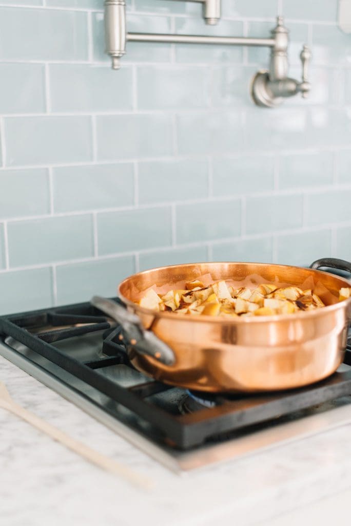 A vintage copper pot filled with apples on a stove top