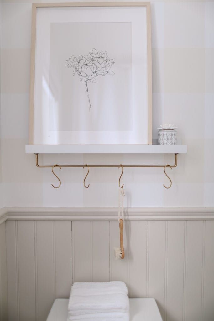 A shelf with a brass rod and hooks mounted beneath