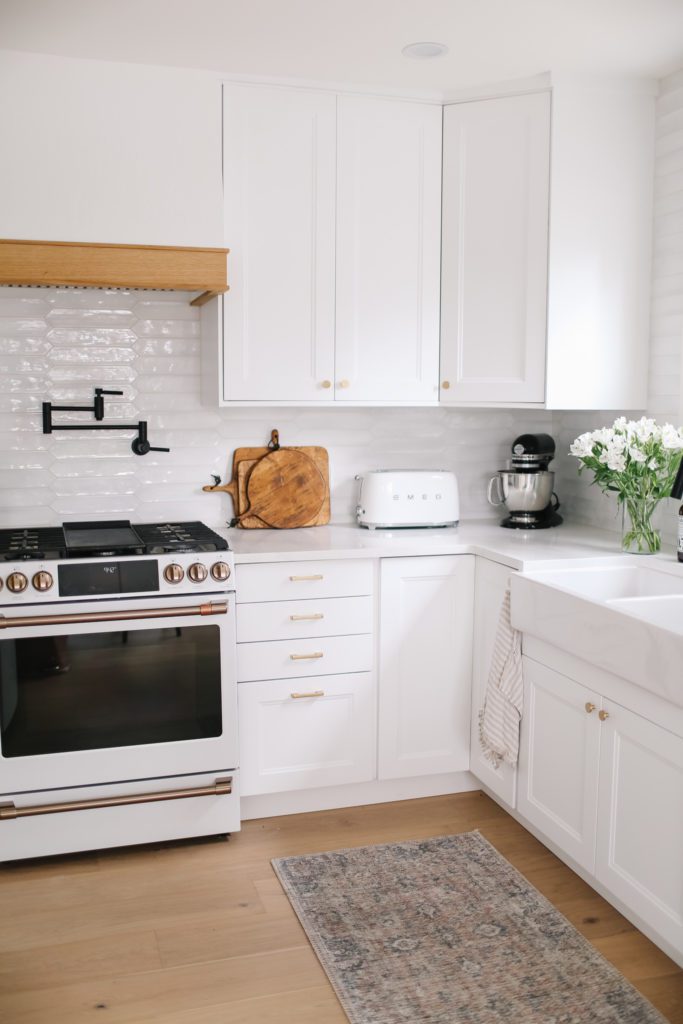 A white kitchen with black pot filler faucet and white stove