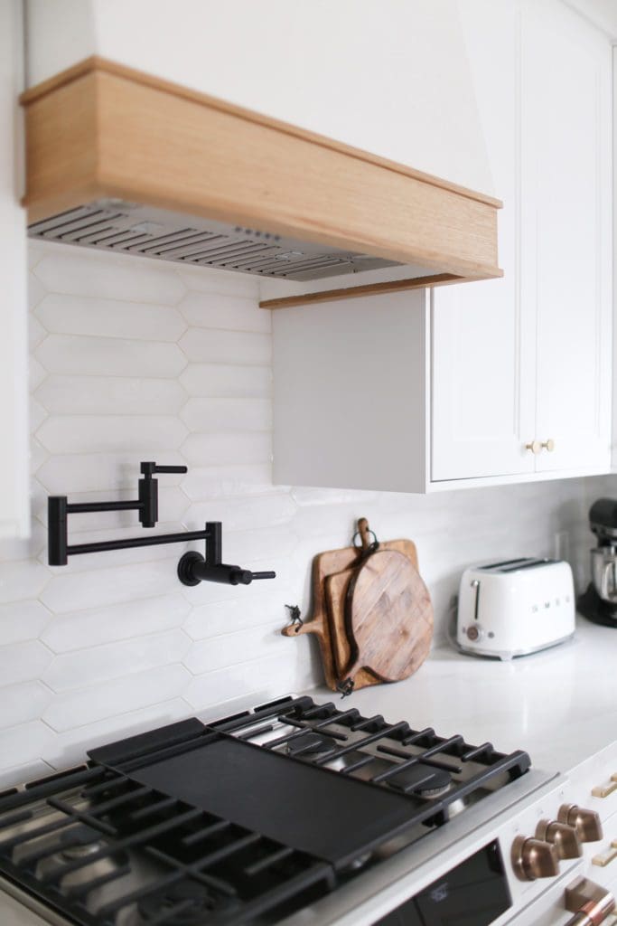 Black pot filler faucet in a white kitchen