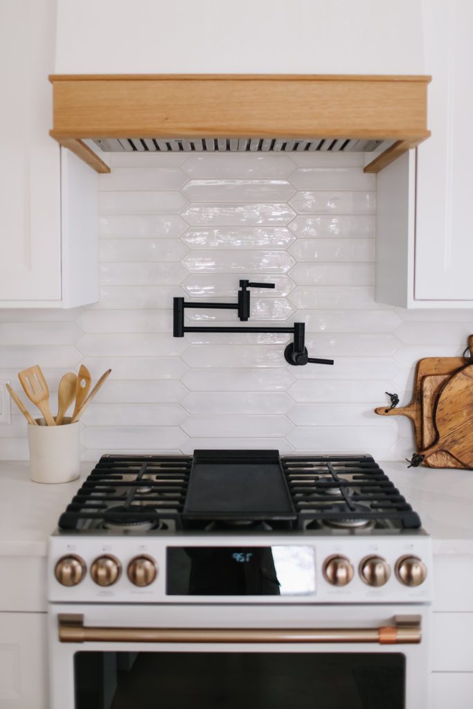 A black pot filler faucet on white tile background in a white kitchen