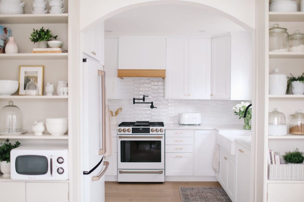 A white kitchen with a white stove and white oak trimmed hood