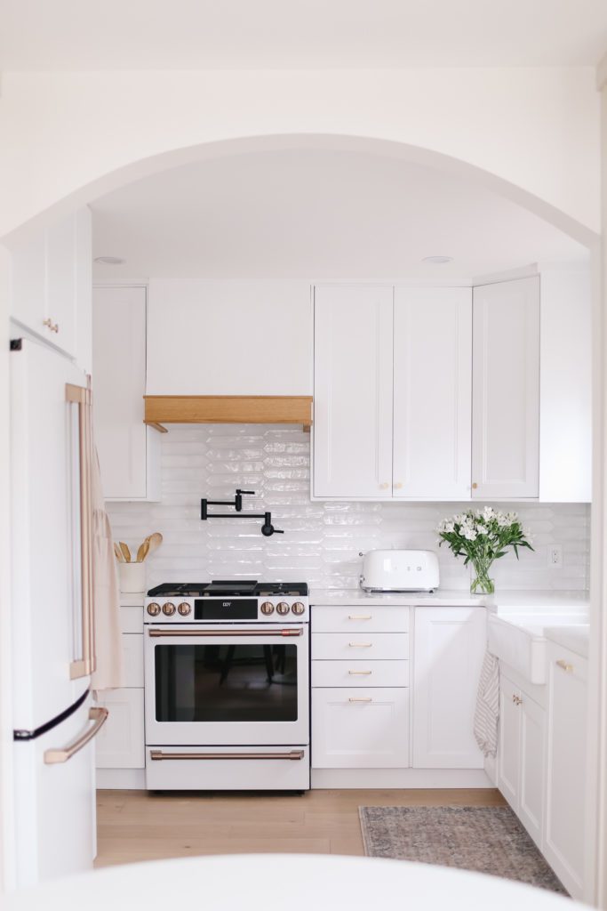 A view through an archway to a small white kitchen