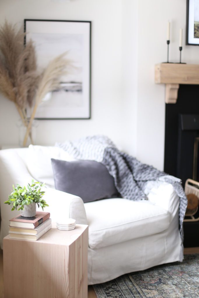 A comfy white chair with gray pillows and blankets