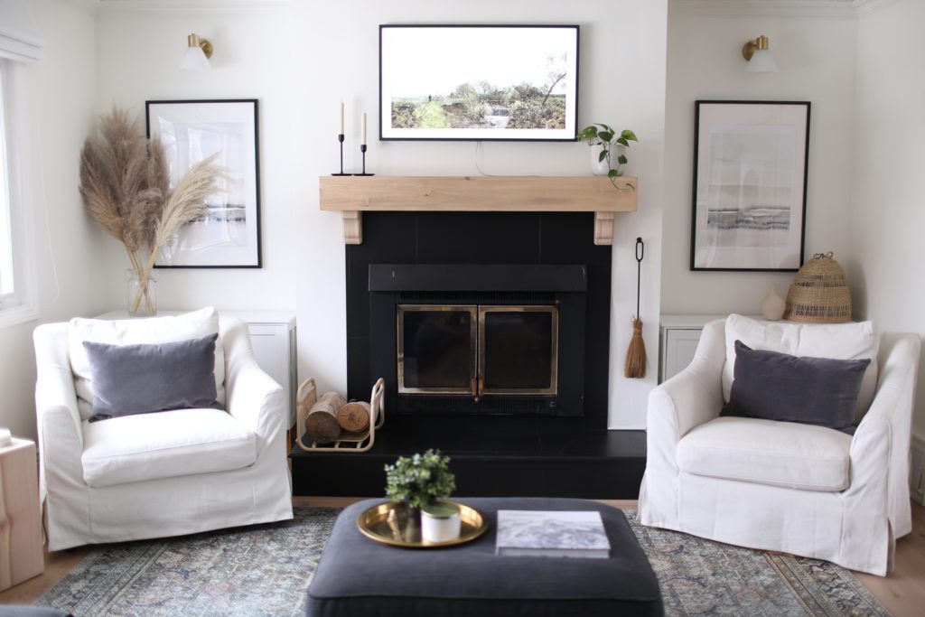 A black wood burning fireplace with white oak mantle and Samsung Frame TV mounted above