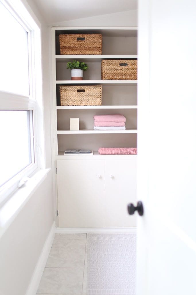 Shelves in a bathroom with baskets and pink towels