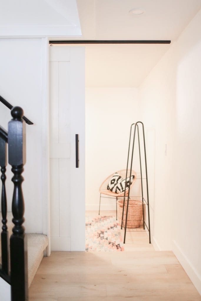 A bedroom with a sliding barn door opens off the bottom of the stairs to the basement in this 1950s character house