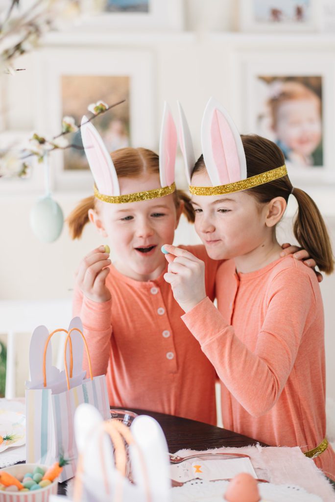 2 little girls look at mini eggs wearing bunny ears