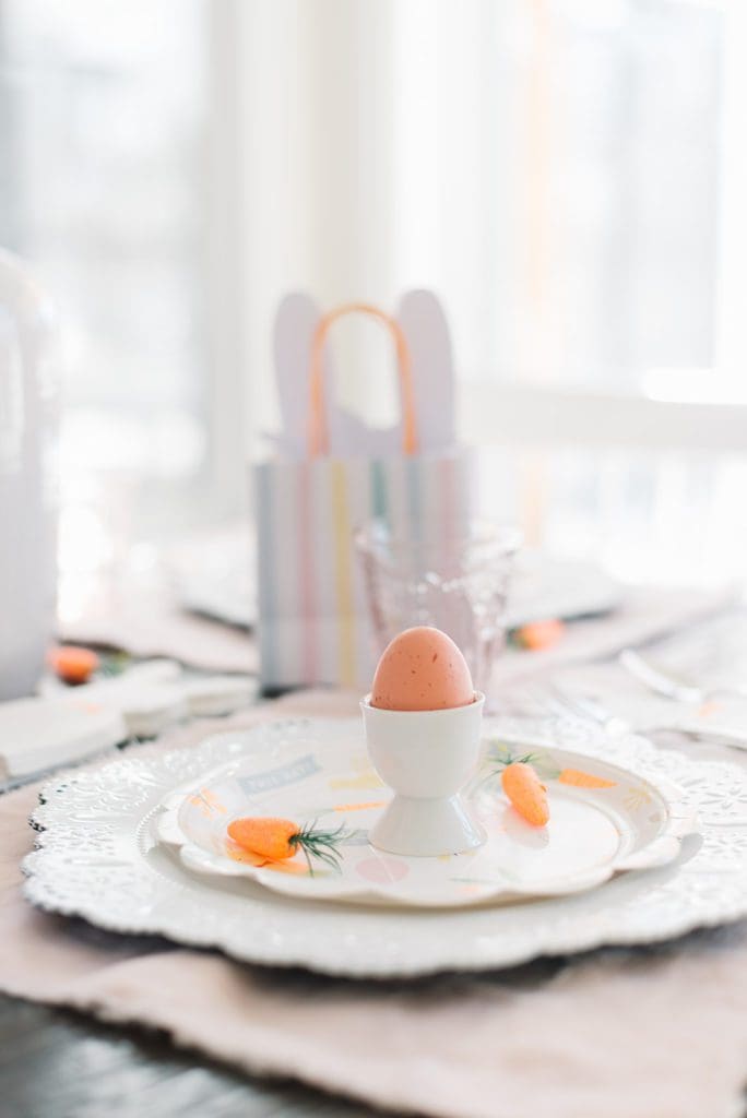 An egg in an egg cup with little carrots beside it