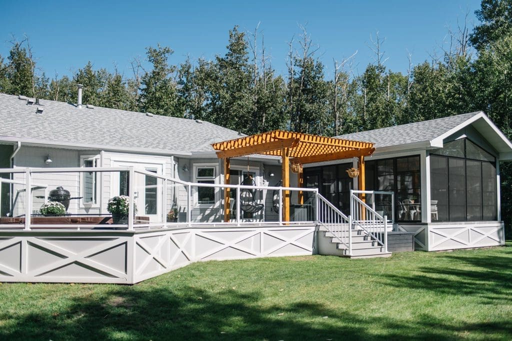 A large back deck with glass railings and a cedar pergola