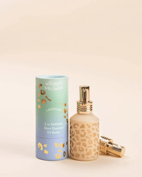 A leopard print spray bottle with gold top sits beside a colourful package