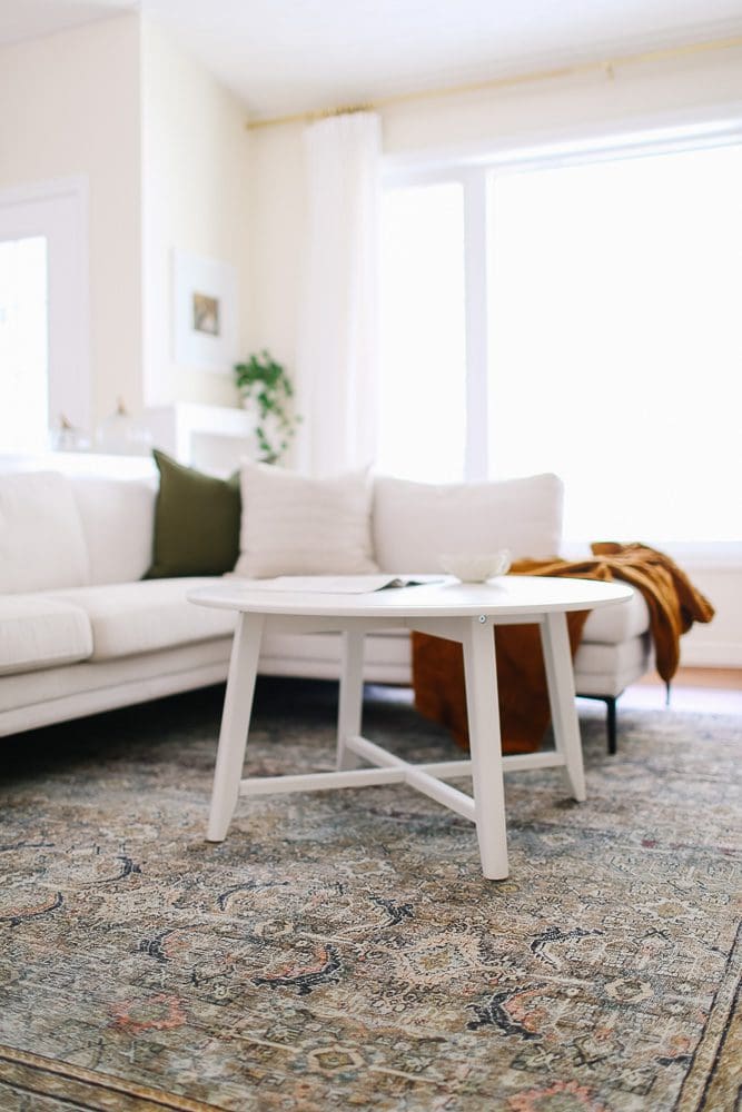 Living room with a sectional, round white coffee table and vintage rug