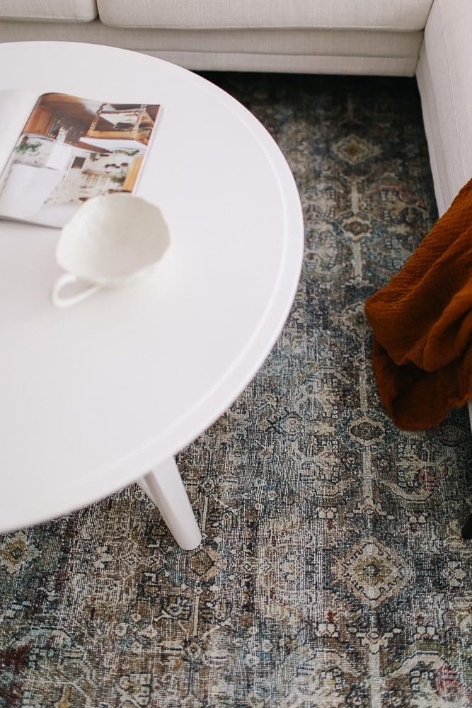 close up of a vintage style rug underneath a white coffee table