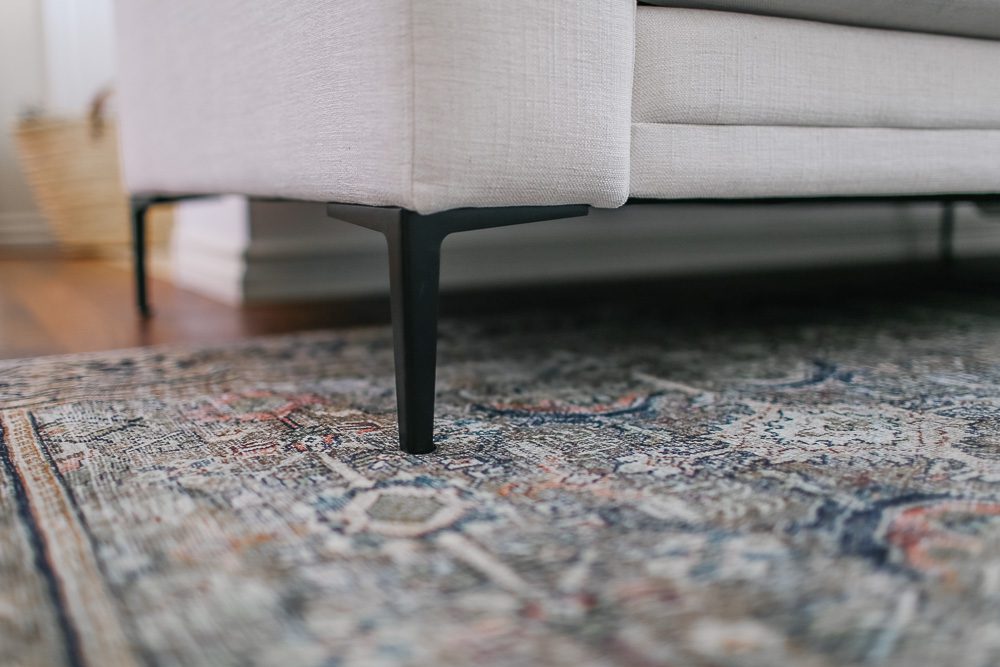 Foot of sectional sofa sitting on a vintage rug